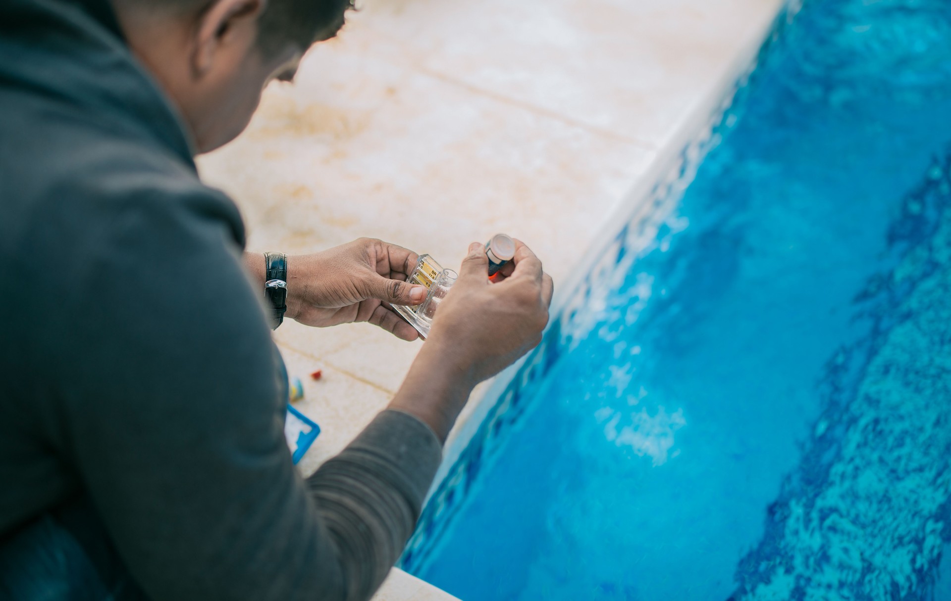 Tester kit to measure chlorine and ph in swimming pools. Person testing the PH of the pool